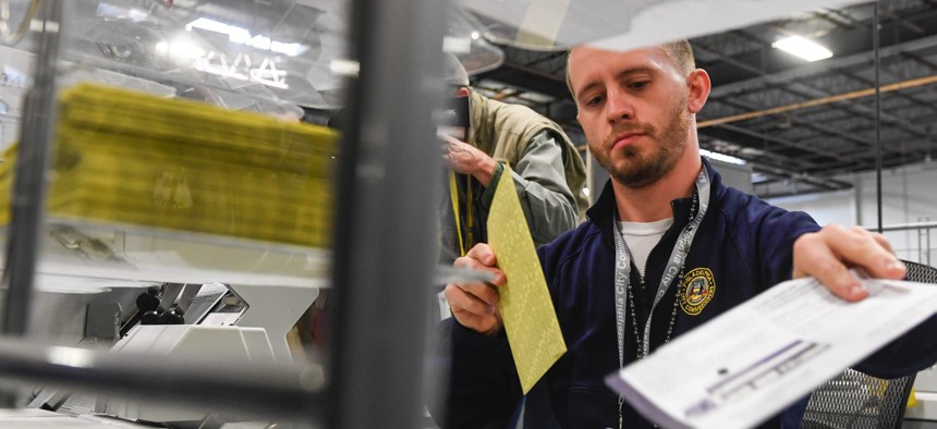 A Philadelphia poll worker demonstrates security steps for handling ballots before November’s presidential election. States have relied on federal partners to boost election security.