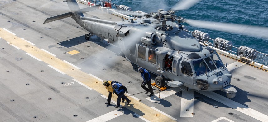 Sailors on the amphibious assault ship USS Iwo Jima (LHD 7), move to safety after chocking and chaining down an MH-60S Seahawk helicopter while underway, March 25, 2025.